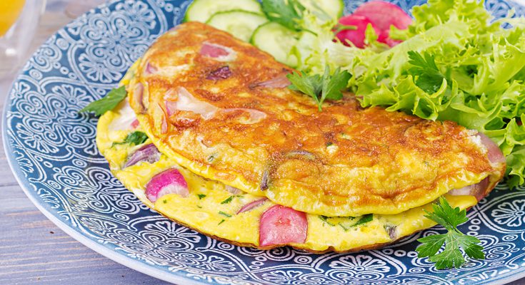 Breakfast. Omelette with radish, red onion and fresh salad on bl